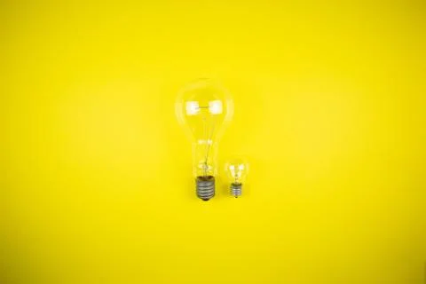 Two bulbs - large and small. Yellow background Stock Photos