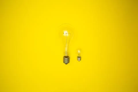 Two bulbs - large and small. Yellow background Stock Photos