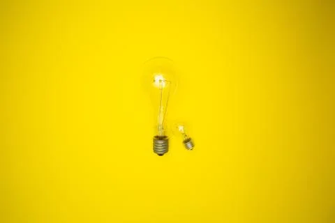 Two bulbs - large and small. Yellow background Stock Photos