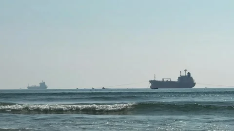 Two Bulk carrier ships silhouettes on the beach horizon and rolling waves Stock Footage 341544006