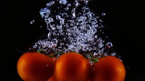 Two bunches of red tomatoes dropping into the water in slow motion. 库存影片 77002493