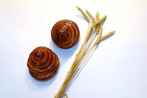 Two buns and spikelets of wheat on a white background. Stock Photos