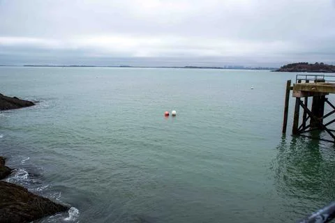 Two buoys float together by a dock along a rocky New England coastline Stock Photos