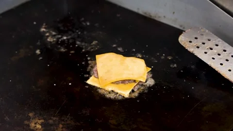 Two burger patties with cheese sizzle on a grill, before the chef picks up Stock Footage 288936675