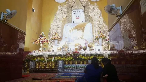 Two Burmese women sit at foot of big seated Buddha statue, Kyauktawgyi pagoda Stock Footage