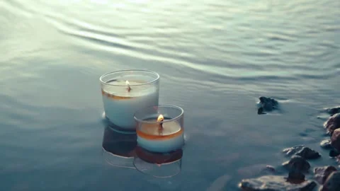 Two burning candles standing in a calm lake water. Slow motion close up view Stock Footage 185436208