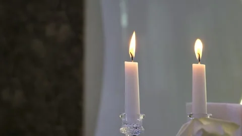Two burning white candles in glass holders on a light background Stock Footage 345115105