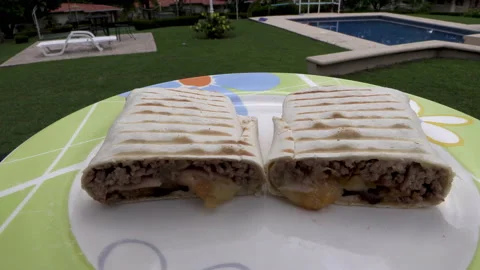 Two Burritos with meat on a plate cut in half Mexican dish food Stock Footage 194445231