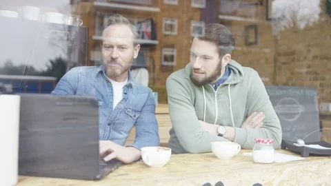 Two business executives using laptop and having a discussion over coffee Stock Footage 108003588
