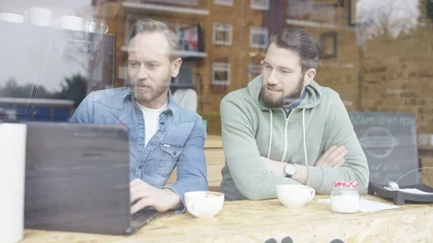 Two business executives using laptop and having a discussion over coffee Stock Footage 108003747