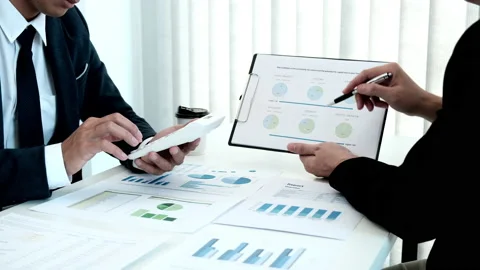 Two business men brainstorming analyzing graph data and coming up with new id Stock Footage 195082200