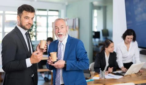 Two business men of different ages employees drinking hot coffee and talking Stock Photos