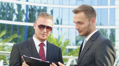 Two business men standing next to an office building to discuss the case Video stock 52820675