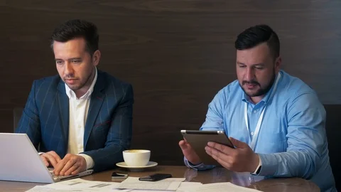 Two business men working on notebook computer and tablet pc in office interior Stock Footage 91375119