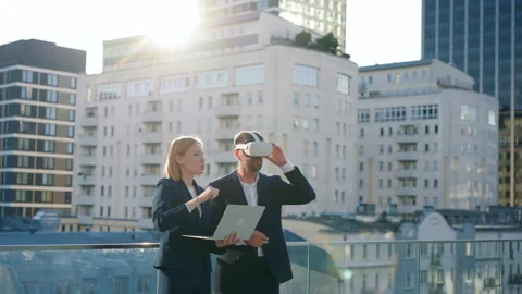 Two business partners man in virtual reality glasses woman with laptop outdoors Stock Footage 249107573