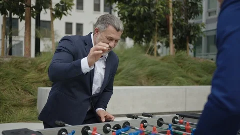 Two business partners play table football outside of office 스톡 동영상 127413317