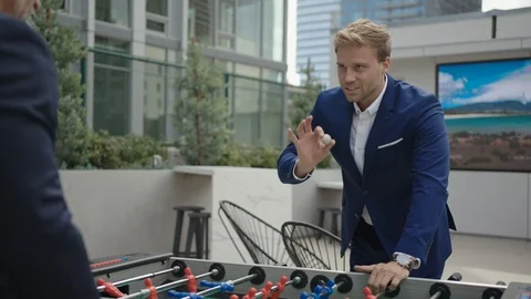 Two business partners play table football outside of office Видео 127413334
