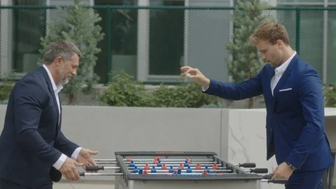 Two business partners play table football outside of office Stock Footage 127413400