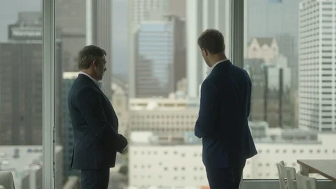Two business partners shake hands in front of view on downtown LA Vidéo 127412968