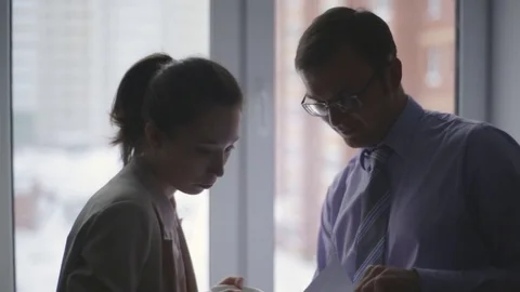 Two business partners standing by the window in office and interacting Stock Footage 72816046