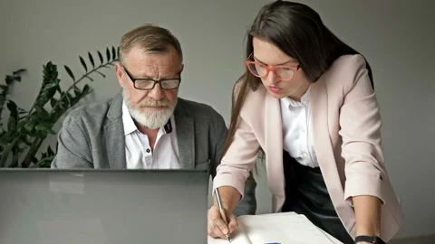 Two business partners work together in the office. Senior man discussing work Stock Footage 138385455