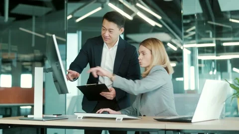 Two business people consulting on a project looking at computer monitor screen  Stock Footage 169365901