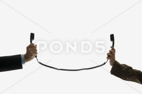 Two business people holding telephone receivers connect with the same cord Stock Photos