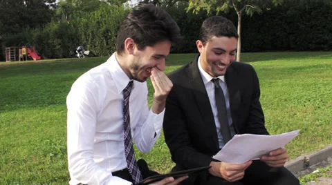 Two business people with tablet computer talk about a project on a park bench Stock Footage 32579771