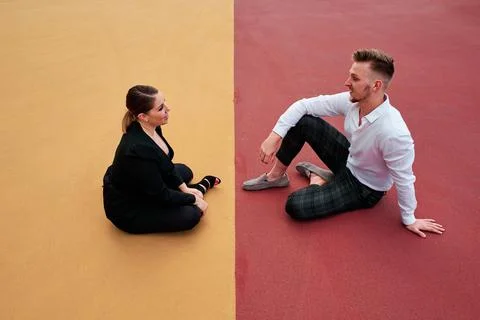 Two business people talking while sitting on floor outdoors. Stock Photos