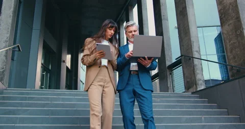 Two business professionals, a man and a woman in formal suits, walk down the sta Stock Footage 330302238