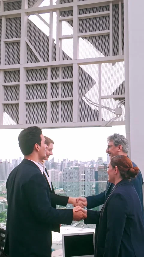 Two business professionals shake hands outdoors on a rooftop, while colleague Video stock 320862494