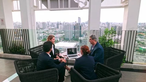 Two business professionals shake hands outdoors on a rooftop, while colleague Video stock 321385660