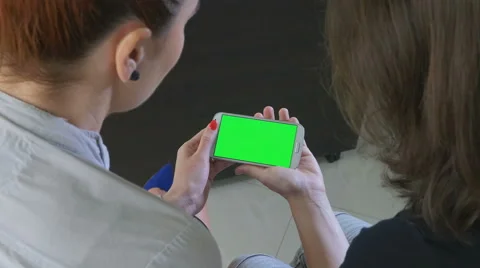 Two business women holding a smartphone with green screen Stock Footage