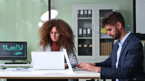 Two business workers talking on the smartphone and using laptop at the office Stock Footage 312383800