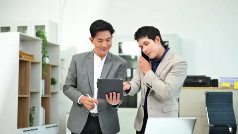 Two business workers talking on the smartphone and using laptop Stock Footage 312714835
