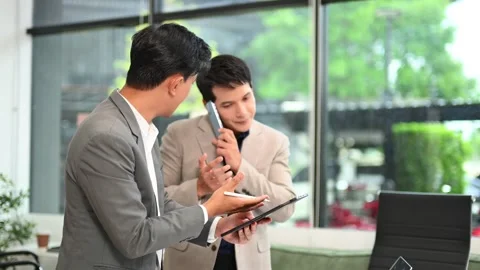 Two business workers talking on the smartphone and using laptop Stock Footage 312714836