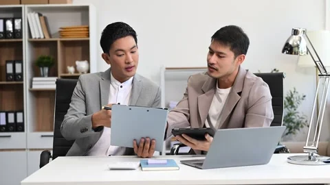 Two business workers talking on the smartphone and using laptop at the office Stock Footage 312980718