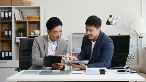 Two business workers talking on the smartphone and using laptop at the office Stock Footage 312980726