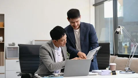 Two business workers talking on the smartphone and using laptop at the office Stock Footage 312980731