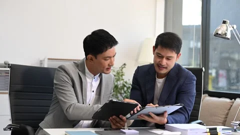 Two business workers talking on the smartphone and using laptop at the office Stock Footage 312980739