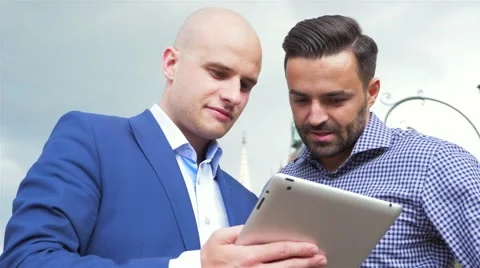 Two businessman are standing and using tablet pc. City background Stock Footage