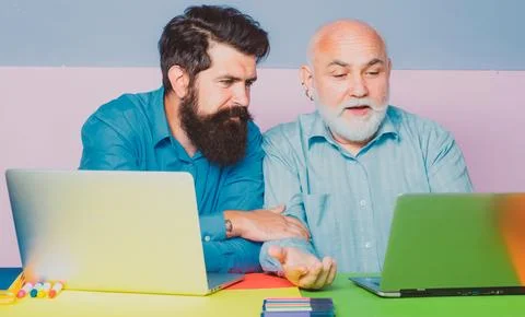 Two businessman sitting at the table typing on laptop computer working with new Stock Photos
