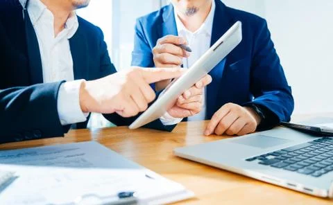 Two businessman using digital tablet to discuss finance and marketing solutio Stock Photos