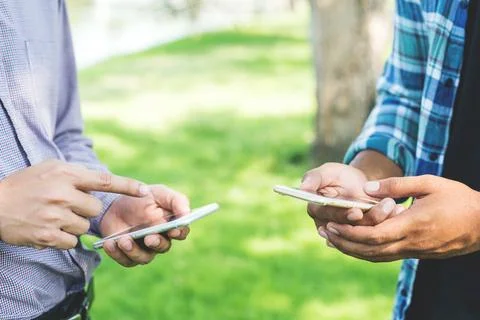 Two businessman using smartphone in the park. Stock Photos
