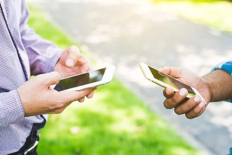 Two businessman using smartphone in the park. Stock Photos