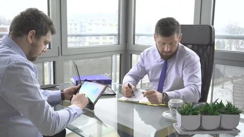 Two businessman working, browsing tablet computer, talking by smartphon, office Vídeos de archivo 73225112