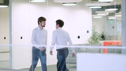 Two businessmen aggressively hit their shoulders in a modern office 動画素材 74863949