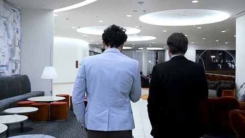 Two businessmen are going through a hall of the business hotel. Back. Slowmotion Stock Footage 70171435