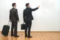 The two businessmen with bags gesture on the white wall background Photo
