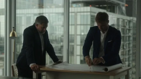 Two businessmen create blueprint in office with view on downtown LA Vidéo 127412684